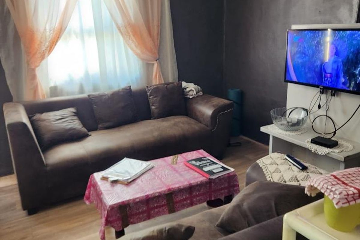 A living room featuring dark painted walls, laminate flooring, and a window with curtain treatments.