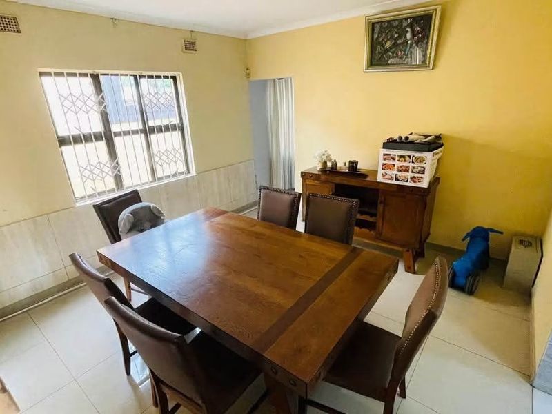 A dining room featuring tiled flooring and a window with security bars, offering a functional space that could benefit from cosmetic updates.
