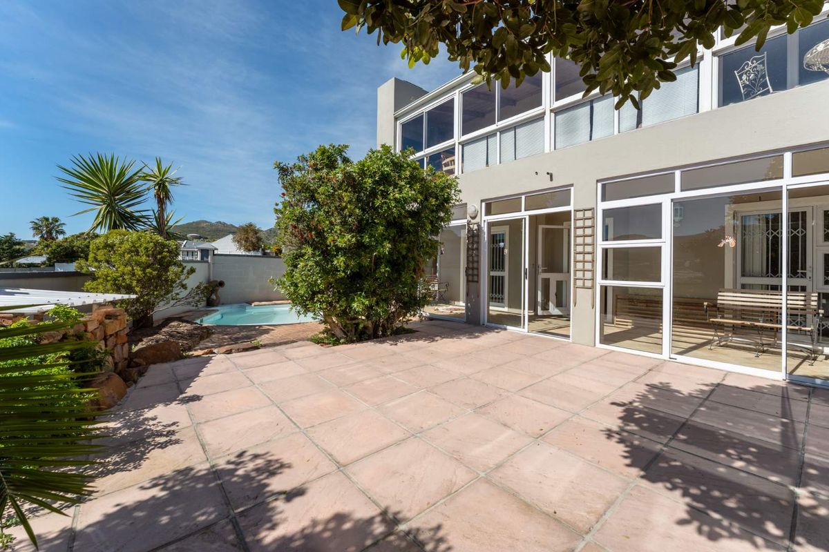 Rear exterior view featuring a paved patio area, a small swimming pool, and large glass sliding doors leading into the apartment.