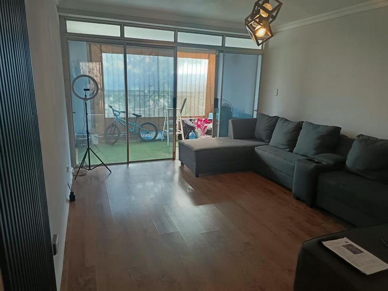 Spacious living room featuring laminate flooring and large sliding glass doors that provide access to an attached balcony area.
