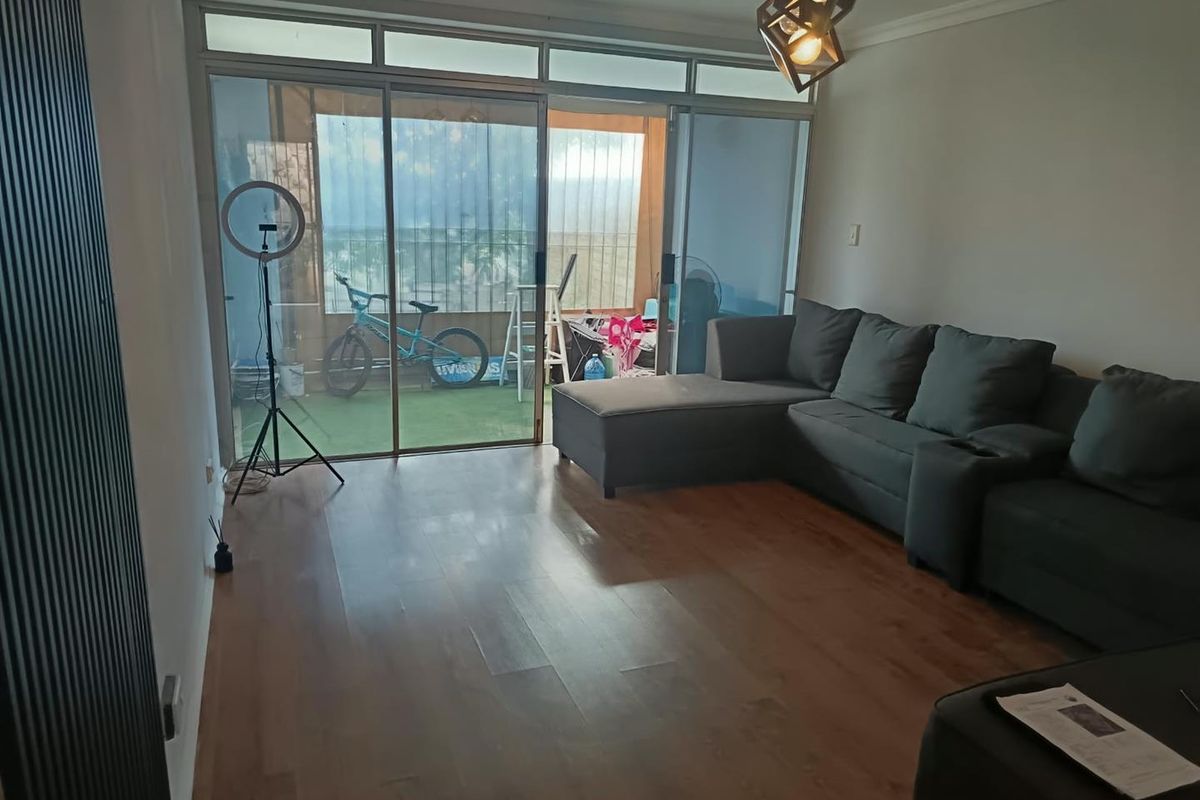 Spacious living room featuring laminate flooring and large sliding glass doors that provide access to an attached balcony area.