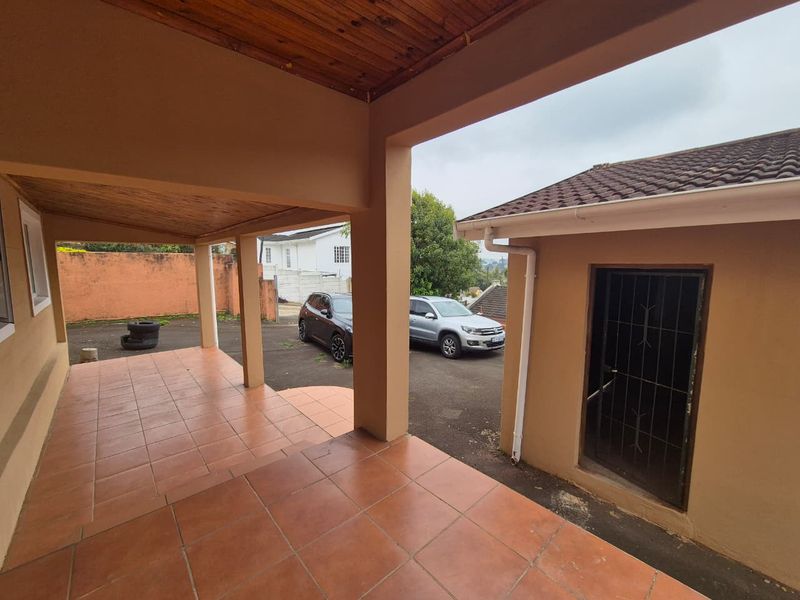 A covered outdoor patio area featuring tiled flooring and a timber ceiling, providing a functional transition space between the building and the driveway.