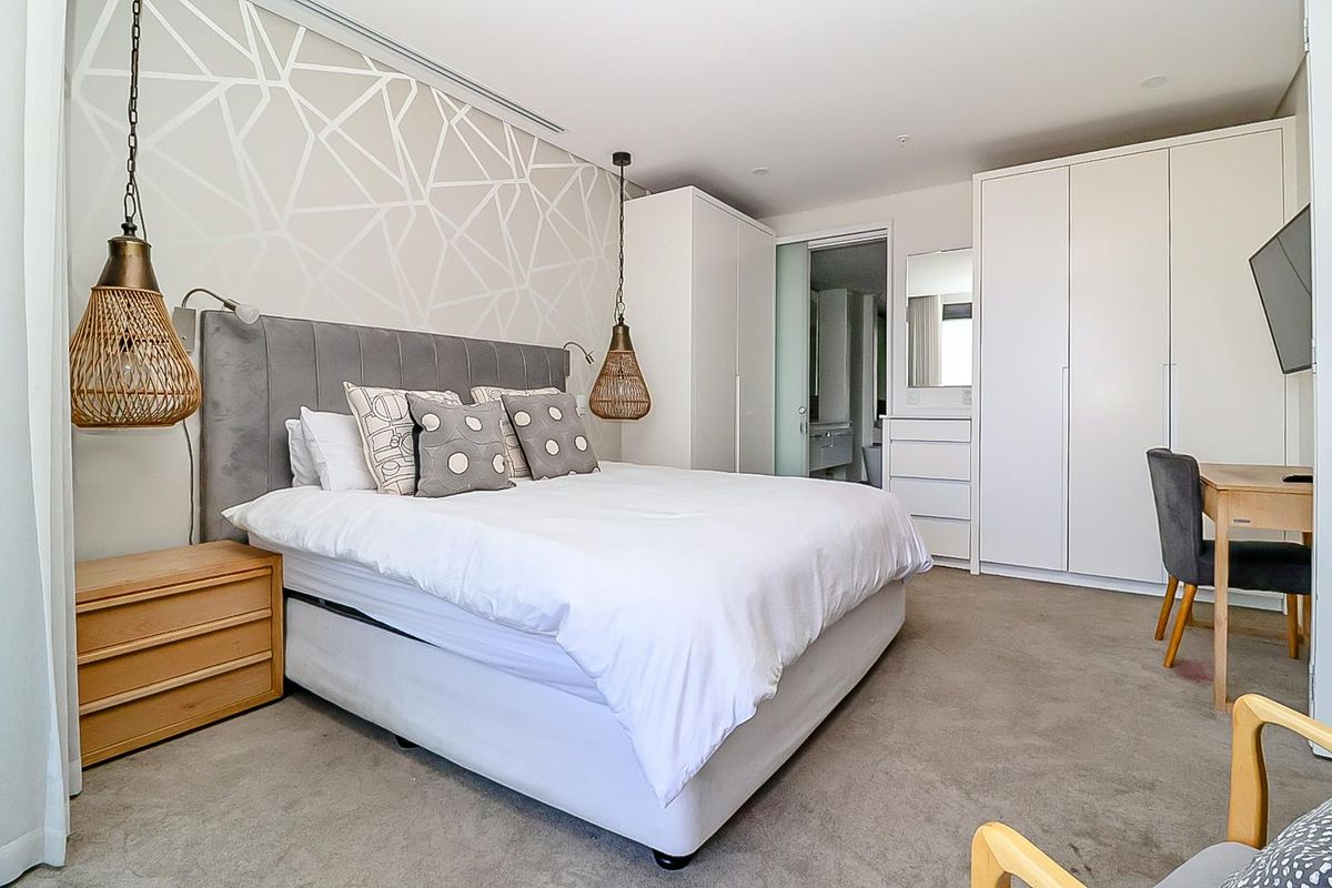 A well-maintained bedroom featuring built-in wardrobes, neutral carpet flooring, and direct access to an en-suite bathroom.