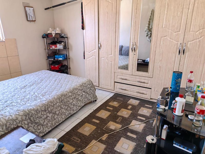 A bedroom featuring light wood-finish built-in wardrobes and tiled flooring, offering functional storage space.