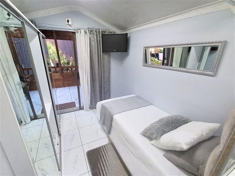 Compact bedroom featuring tiled flooring, a built-in wardrobe, and direct access to an outdoor patio area through sliding glass doors.