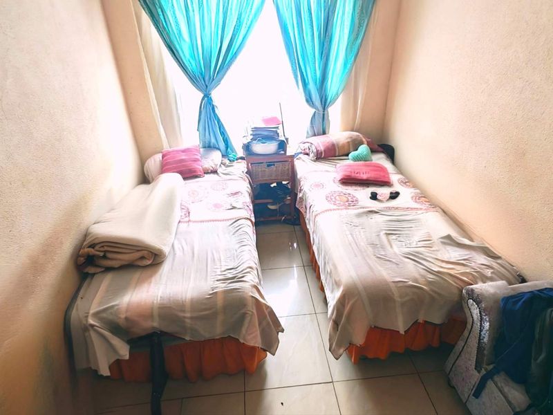 A compact bedroom featuring tiled flooring and natural light from a central window, requiring cosmetic updates to the wall finishes.