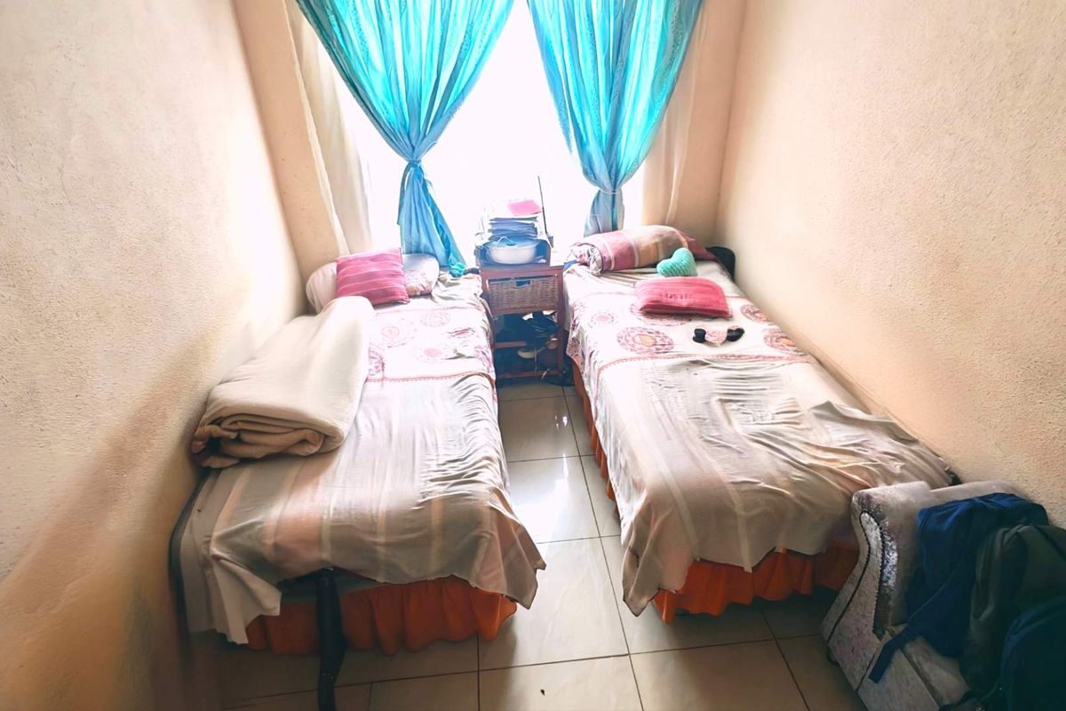 A compact bedroom featuring tiled flooring and natural light from a central window, requiring cosmetic updates to the wall finishes.