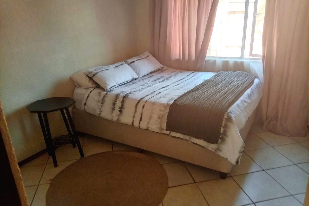 A functional bedroom featuring tiled flooring and a window with curtains, providing a simple and practical living space.