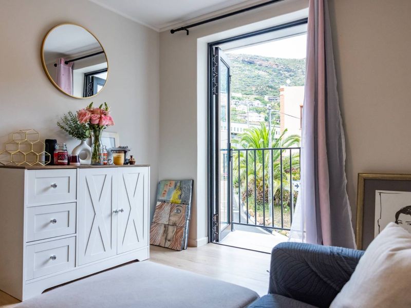 A bright bedroom featuring laminate flooring and a door leading to a private balcony with scenic views.