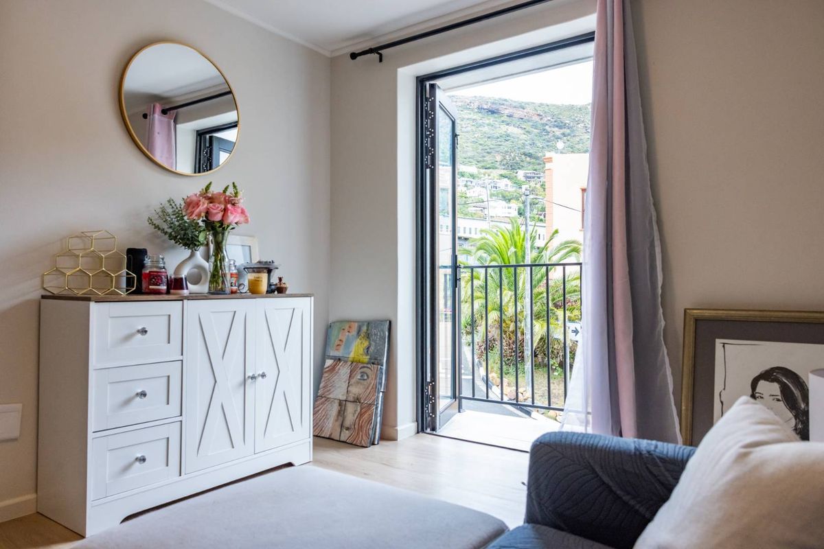 A bright bedroom featuring laminate flooring and a door leading to a private balcony with scenic views.