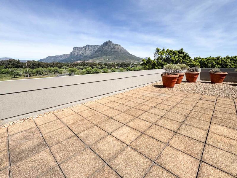 An open-air paved balcony featuring a parapet wall and expansive mountain views.