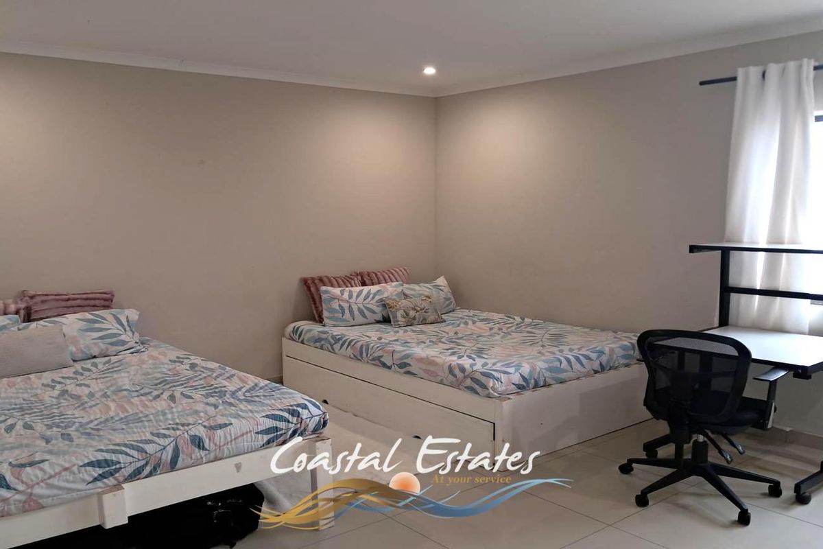 A spacious bedroom featuring neutral wall tones, tiled flooring, and recessed lighting, providing a clean and functional living space.