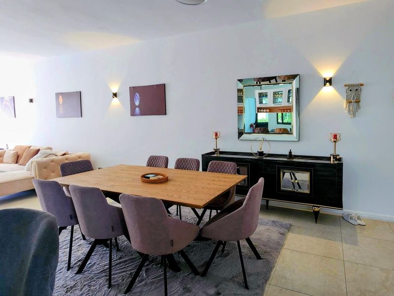Spacious open-plan living and dining area featuring modern wall-mounted lighting and neutral tiled flooring, creating a bright and inviting atmosphere.