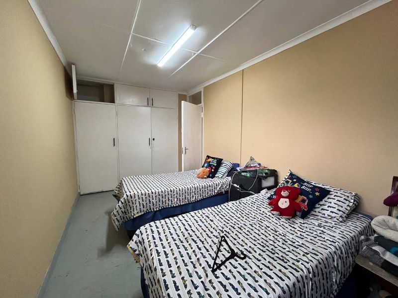 A bedroom featuring built-in cupboards and a fluorescent ceiling light, requiring cosmetic updates to the ceiling and flooring to improve its overall condition.