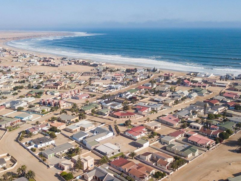 An aerial view of a coastal residential neighborhood situated along the shoreline, showcasing the layout of the properties and proximity to the ocean.