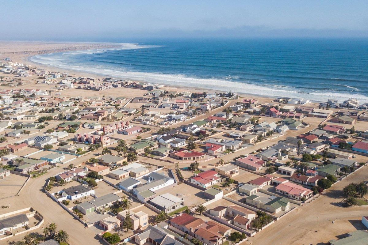 An aerial view of a coastal residential neighborhood situated along the shoreline, showcasing the layout of the properties and proximity to the ocean.