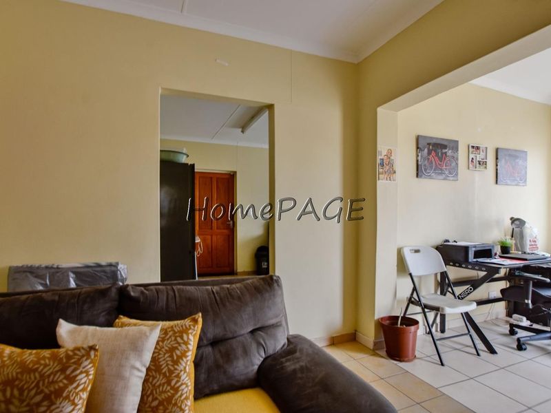 A living area featuring tiled flooring and coved ceilings, providing a functional space with potential for cosmetic updates and modernization.