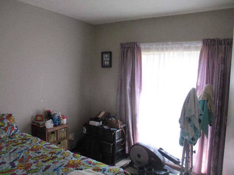 A standard bedroom featuring neutral wall paint and a window with installed curtain rails, providing natural light to the space.