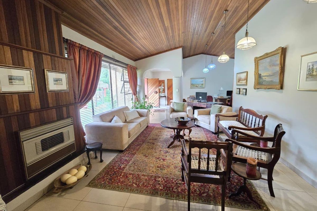 Spacious living room featuring a vaulted timber-clad ceiling, built-in fireplace, and tiled flooring, creating a warm and traditional atmosphere.