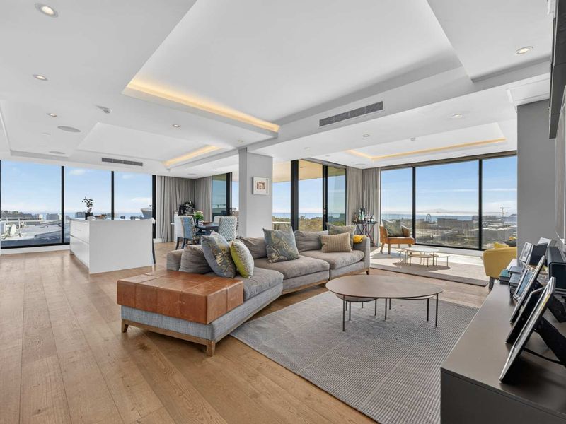 Spacious open-plan living area featuring hardwood floors, recessed ceiling lighting, ducted air conditioning, and expansive floor-to-ceiling windows with panoramic views.