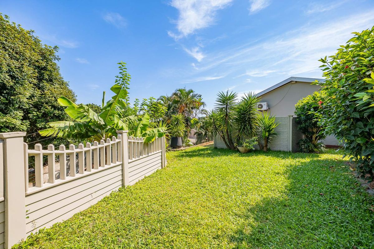 A well-maintained private rear garden featuring a manicured lawn, established greenery, and perimeter fencing, providing a peaceful outdoor space.