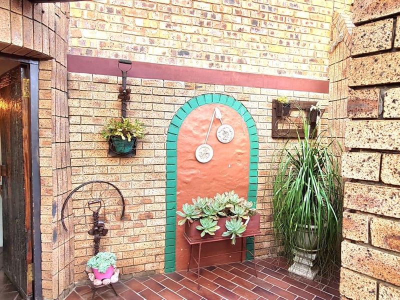 A charming, enclosed patio area featuring rustic face brick walls, tiled flooring, and a decorative arched wall feature.