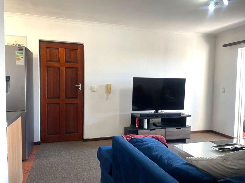 A living room area featuring carpet flooring, coving, and a wall-mounted intercom system.