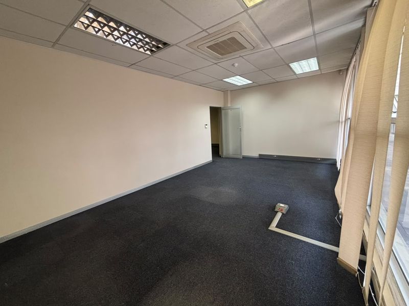 An empty office space featuring a suspended ceiling with recessed lighting, ducted air conditioning, and carpeted flooring with an integrated electrical floor box.