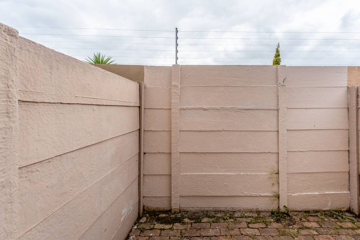 A private rear courtyard area featuring a precast concrete boundary wall with integrated electric fencing and brick paved flooring.