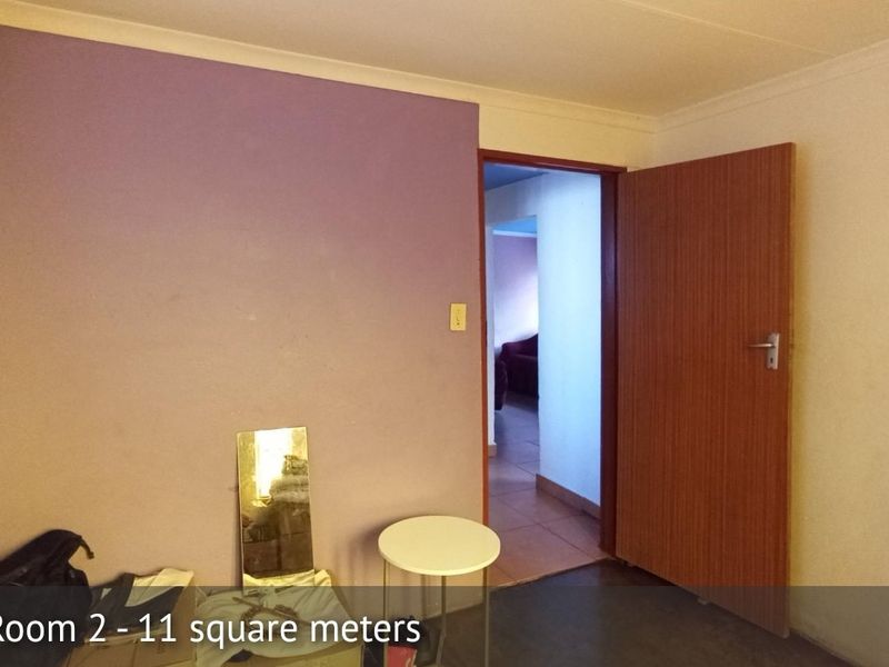 A vacant bedroom featuring a single accent wall, standard door, and electrical fixtures, offering a blank canvas for potential interior updates.