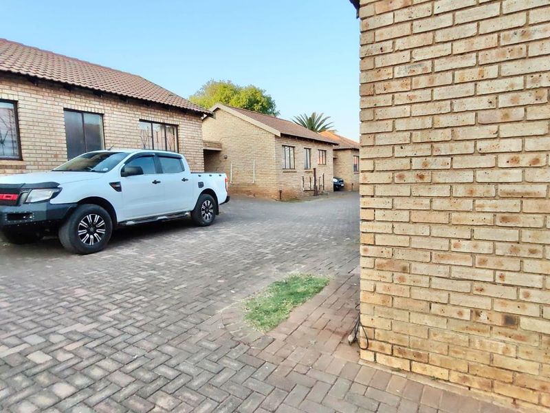 Exterior view of a townhouse complex featuring face brick construction, a tiled roof, and a paved driveway area.