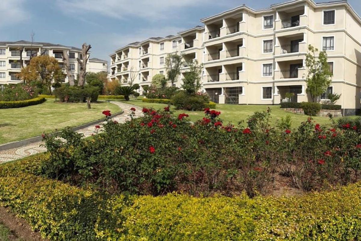 A well-maintained apartment complex featuring landscaped gardens, paved walkways, and multi-story residential buildings with private balconies.