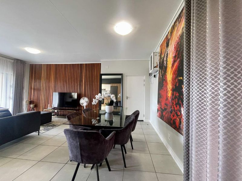 Spacious open-plan living and dining area featuring modern tiled flooring, a striking timber slat feature wall, and integrated air conditioning.
