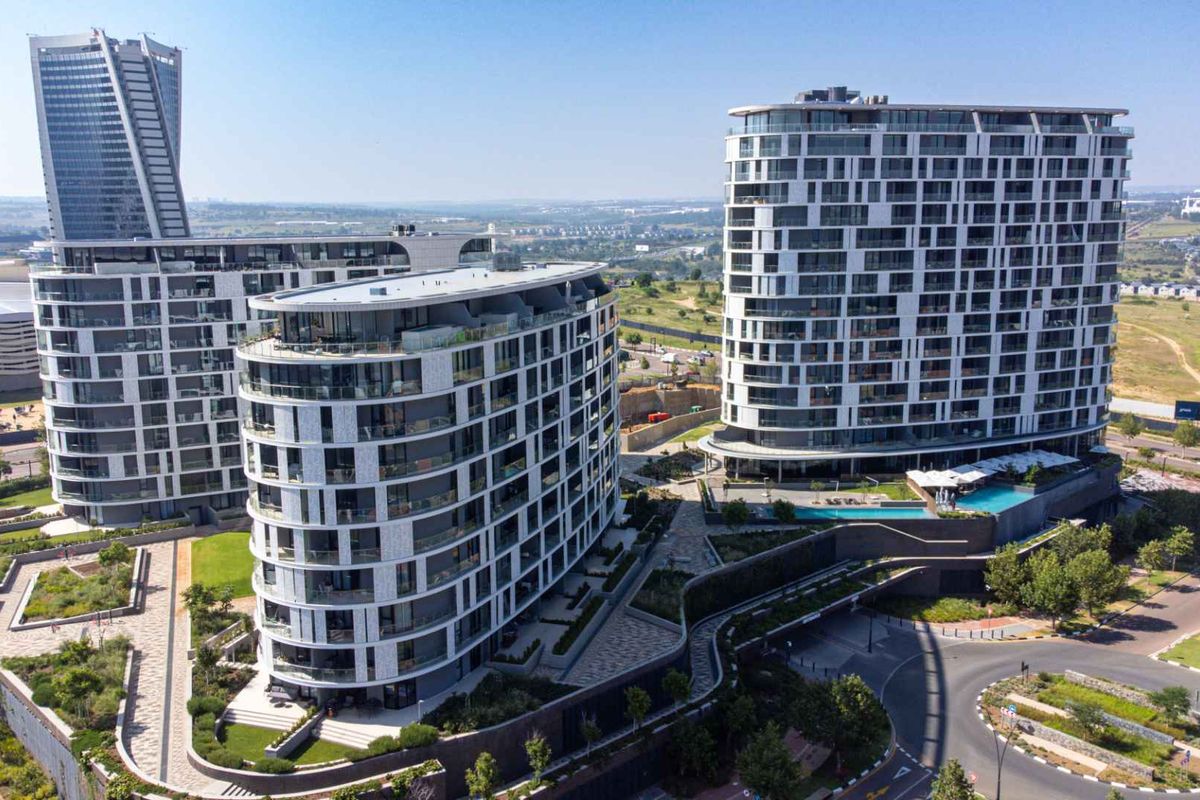 Aerial view of a modern luxury penthouse apartment complex featuring contemporary architectural design, landscaped grounds, and integrated swimming pool facilities.