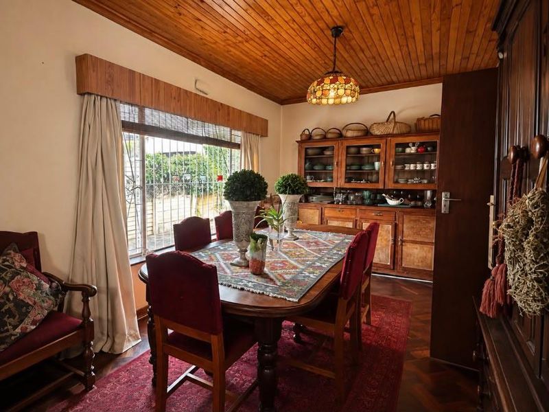 A traditional dining room featuring warm timber ceilings, parquet flooring, and extensive built-in wooden cabinetry for storage.