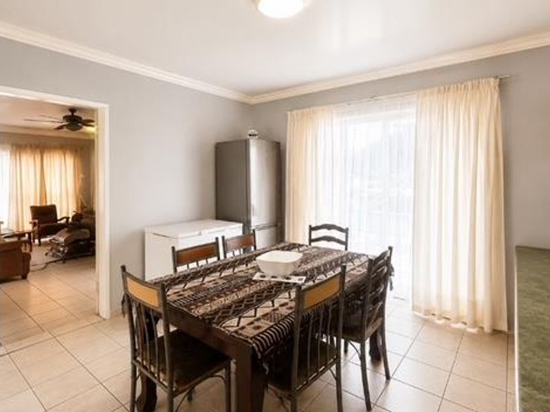 Open plan dining area featuring tiled flooring, sliding door access to the exterior, and adjacent kitchen cabinetry with laminate countertops.