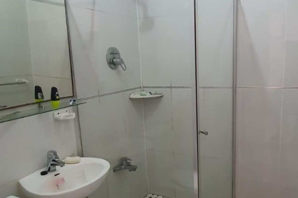 A functional bathroom featuring a pedestal basin, a glass-enclosed shower, and tiled finishes throughout.