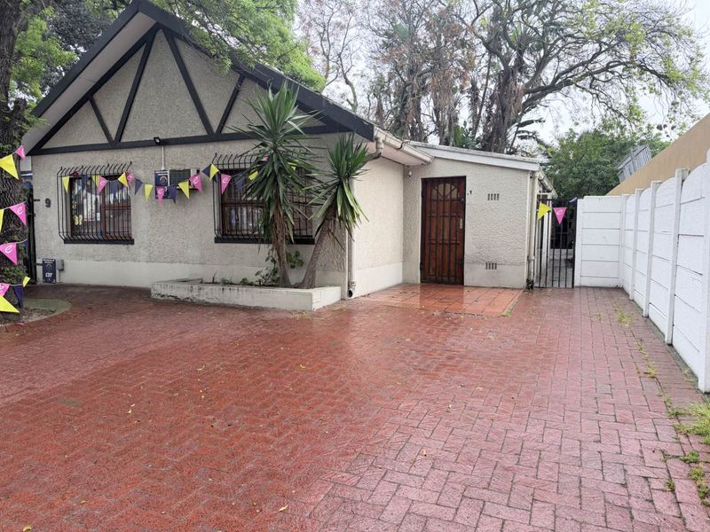 Front exterior view of a house featuring a brick-paved driveway, security bars on windows, and a gabled roof design.