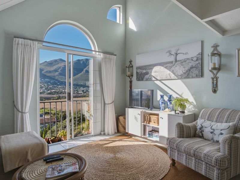 Bright living room featuring a vaulted ceiling, arched window, and sliding glass door leading to a balcony with scenic mountain views.