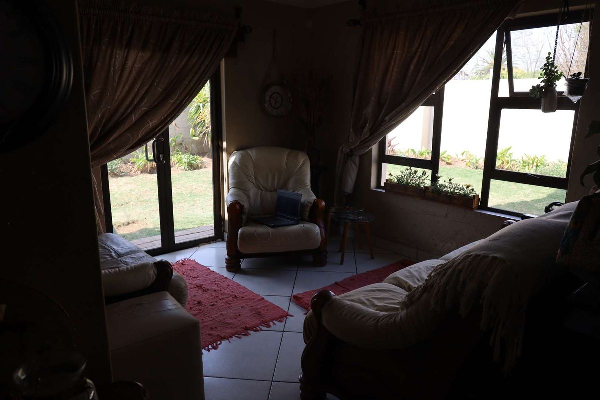 A living room featuring tiled flooring, large windows, and sliding glass doors that provide direct access to the garden area.