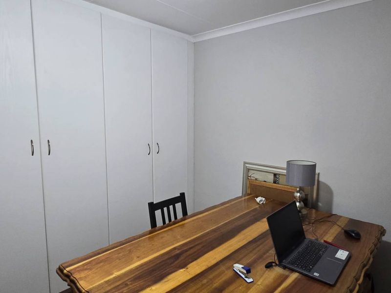 A bedroom featuring neutral walls and floor-to-ceiling built-in cupboards, providing ample storage space.