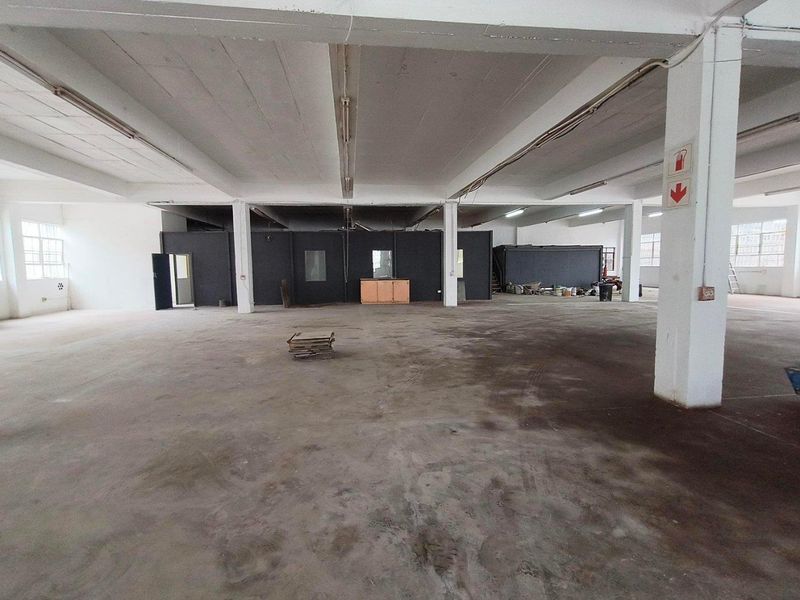 Spacious industrial warehouse or utility area featuring open-plan layout, concrete flooring, exposed structural columns, and functional overhead lighting.