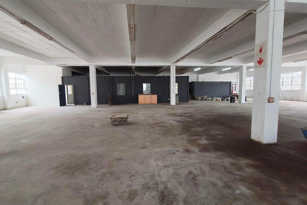 Spacious industrial warehouse or utility area featuring open-plan layout, concrete flooring, exposed structural columns, and functional overhead lighting.