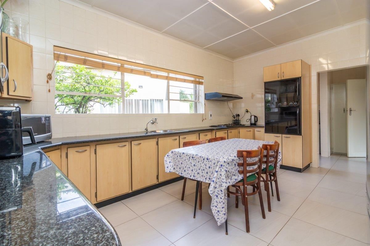 A functional kitchen featuring light wood cabinetry, dark granite countertops, tiled walls, and a built-in oven, offering a practical layout for daily meal preparation.