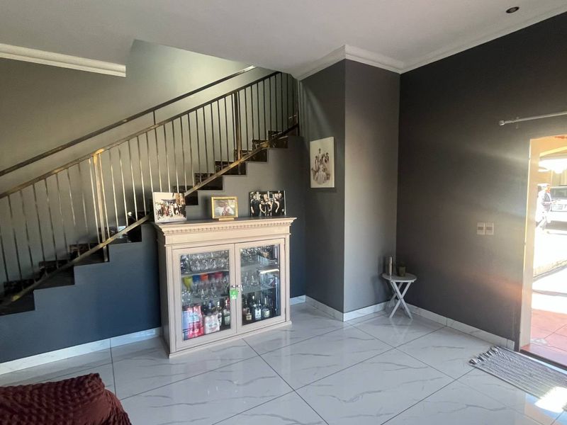 Entrance area featuring a modern staircase with metal balustrade, polished tiled flooring, and neutral grey wall finishes.