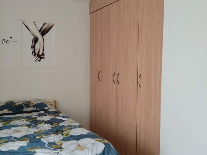 A bedroom featuring light wood-finish built-in wardrobes and tiled flooring, providing functional storage space.