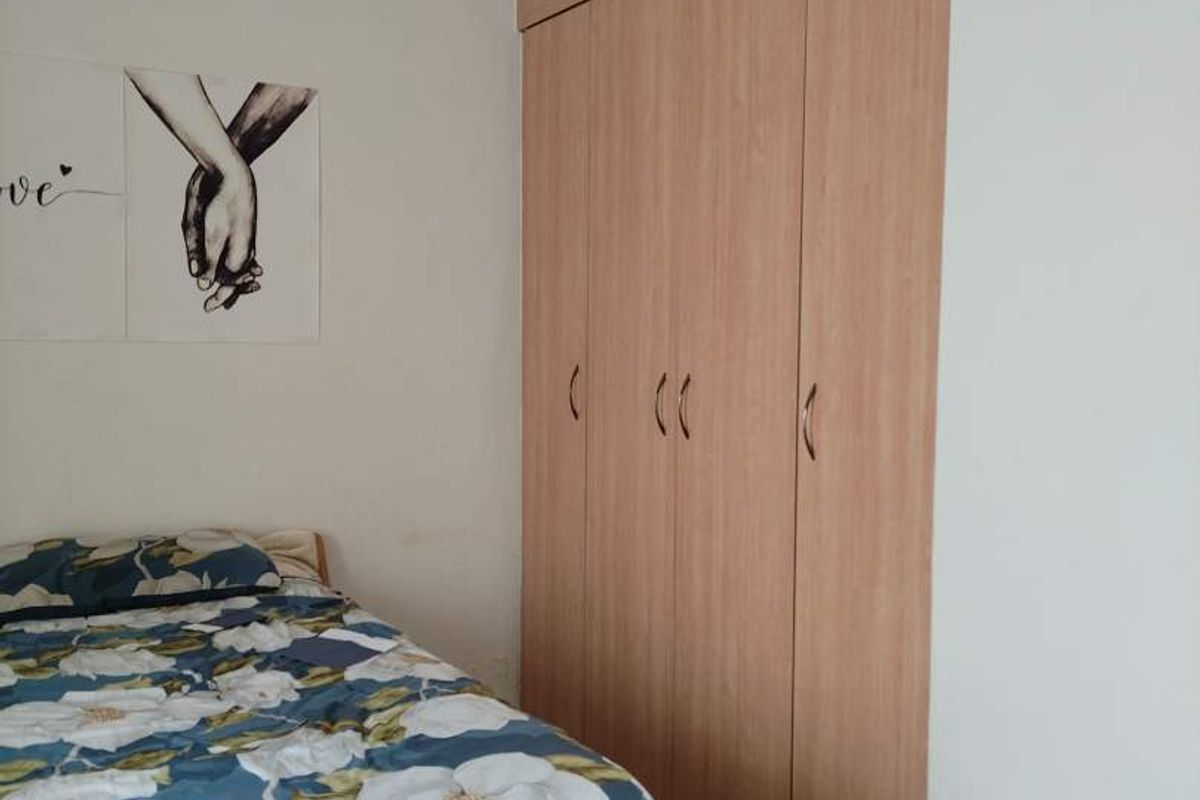 A bedroom featuring light wood-finish built-in wardrobes and tiled flooring, providing functional storage space.