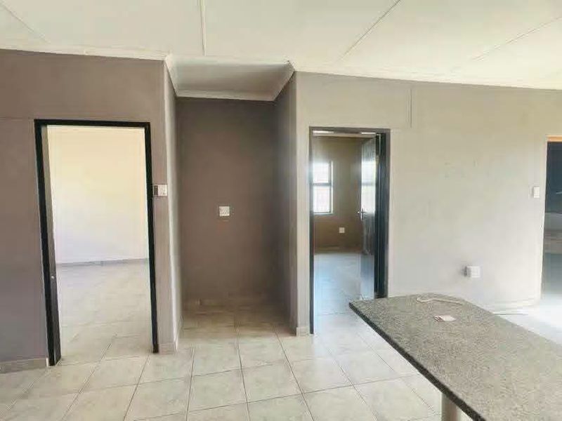 An open-plan living area featuring tiled flooring and a granite breakfast bar, providing a neutral canvas for interior design.