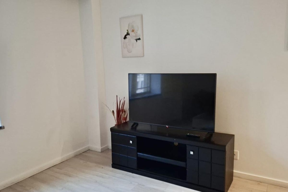 A living room area featuring light-toned laminate flooring and a window with a tiled sill.