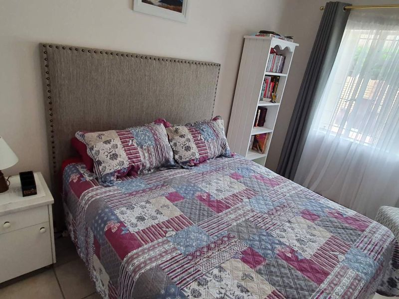 A cozy bedroom featuring tiled flooring and a window with installed curtain rails, providing natural light.